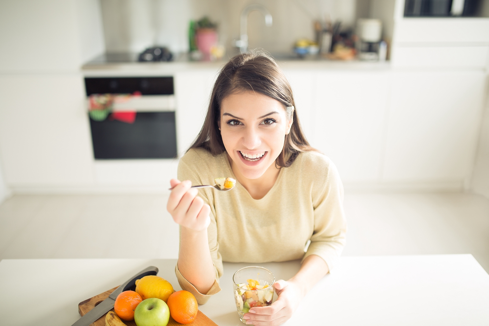 Holmes Place | femme mangeant une salade de fruits saine et heureuse